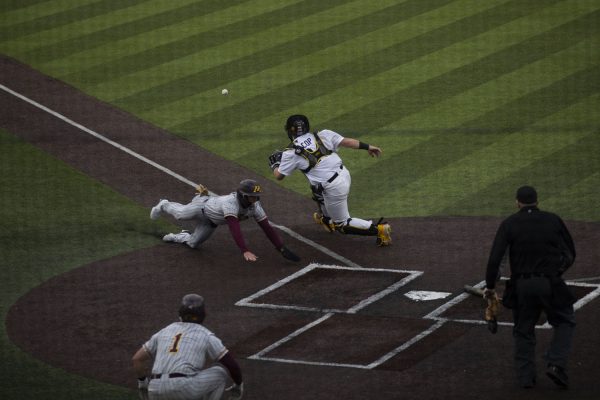 Iowa catcher David Cop lunges for the ball as a Minnesota baserunner scores a run during a baseball game between Iowa and Minnesota at Duane Banks Field on Friday, March 29, 2024. The Gophers defeated the Hawkeyes 16-9.