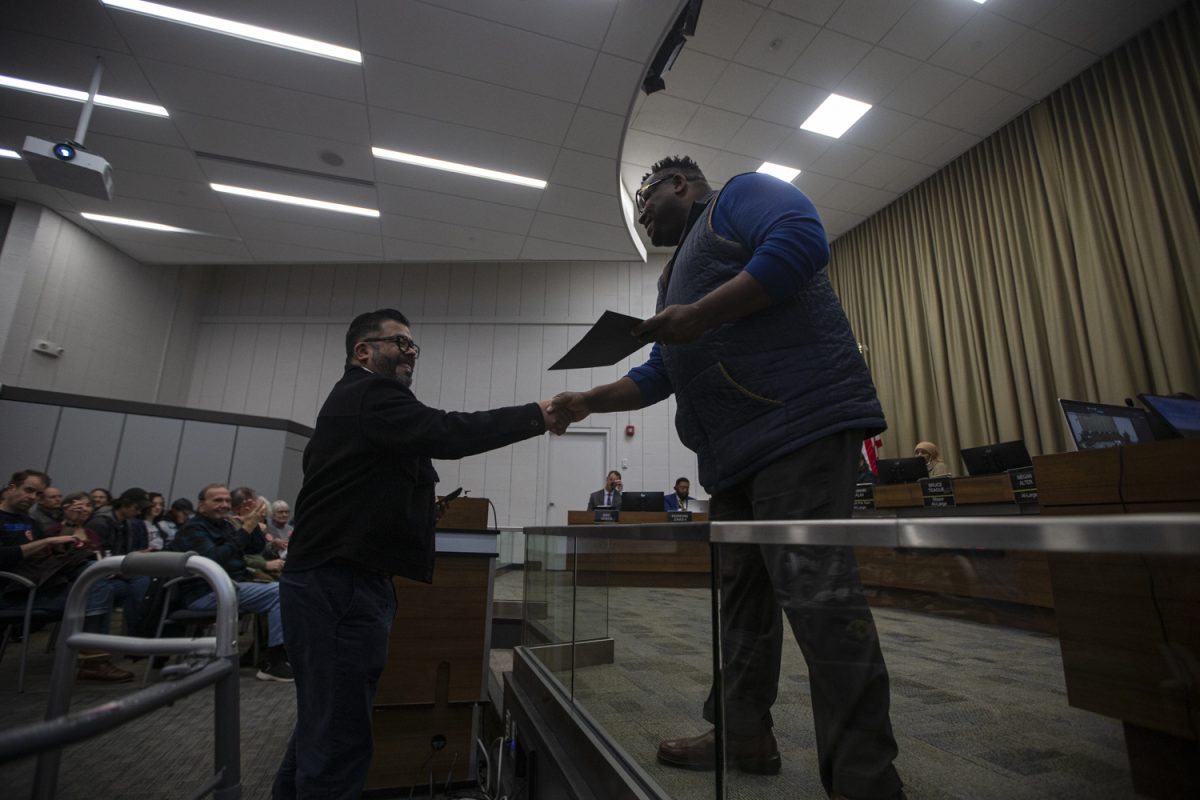 Mayor At-Large Bruce Teague shakes a hand during an Iowa City City Council Meeting on Tuesday, April 2, 2024. 