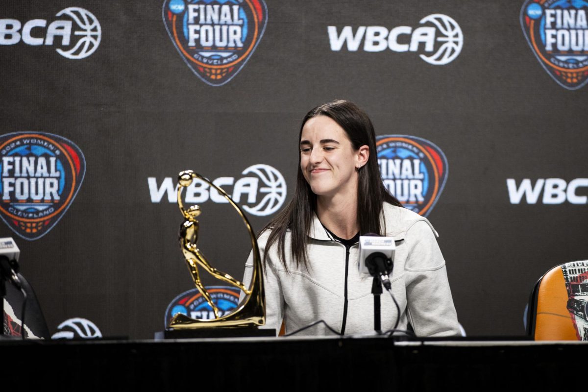 Iowa guard Caitlin Clark smiles down at the WBCA Wade Trophy during the award news conference at Rocket Mortgage Field House in Cleveland, Ohio, on Thursday, April 4, 2024.