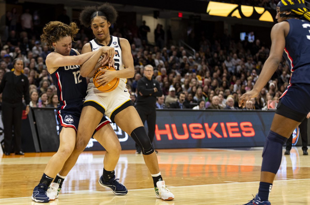 UConn guard Ashlynn Shade and Iowa forward Hannah Stuelke fight over the ball during a NCAA Tournament Final Four game between No. 1 Iowa and No. 3 UConn at Rocket Mortgage FieldHouse in Cleveland, Ohio, on Friday, April 5, 2024. The Hawkeyes defeated the Huskies, 71-69.