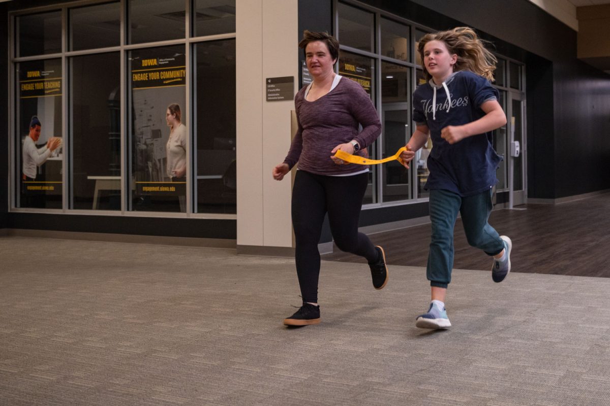 Bettina Dolinsek (left) who is visually impaired, is guided by Bianca Banse while running at the Old Capitol Mall in Iowa City on Sunday, April 28, 2024.