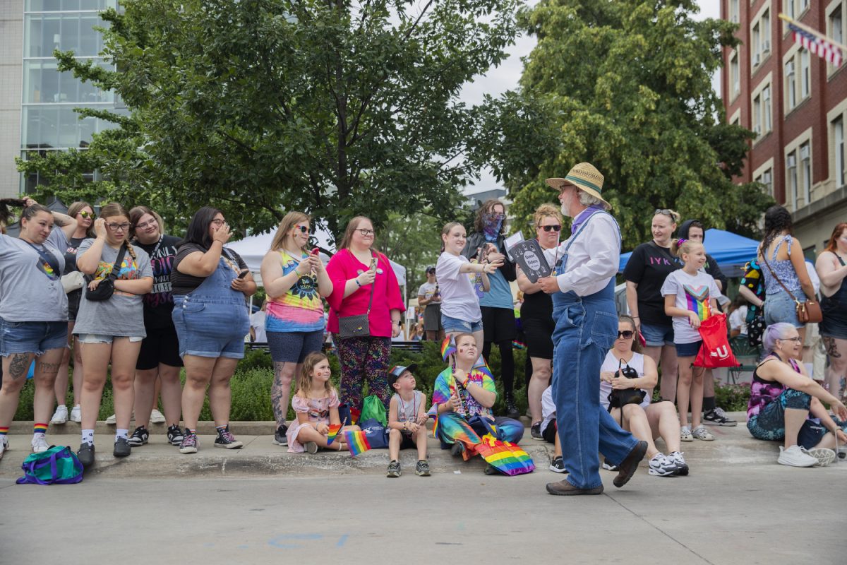 A queer elders member hands out fans to attendees during the 53rd annual pride parade in downtown Iowa City on Saturday, June 15, 2024. The event included a parade, performances, and local vendor stations around downtown.