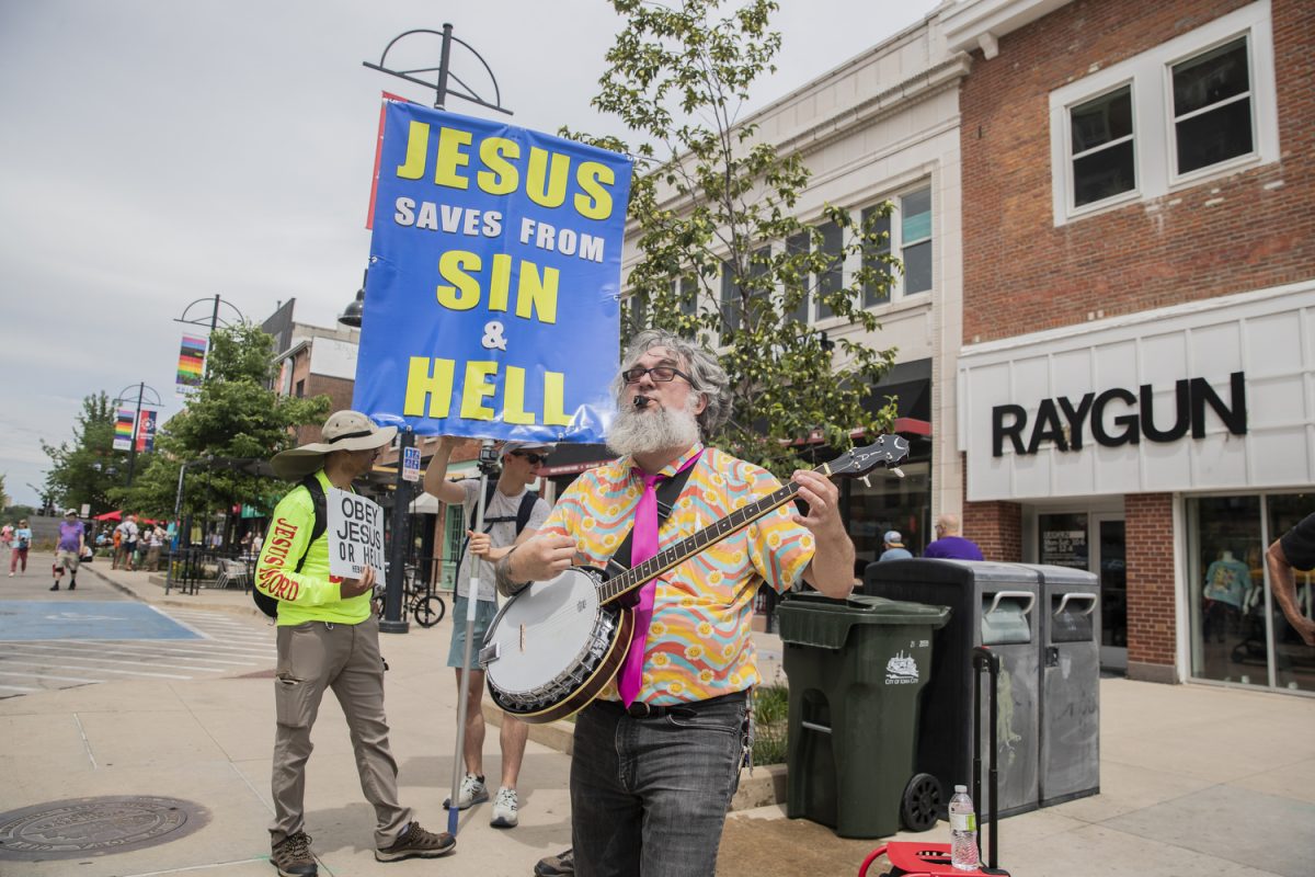 A counter protestor plays a song in front or protestors during the 53rd annual pride festival in downtown Iowa City on Saturday, June 15, 2024. The event included a parade, performances, and local vendor stations around downtown.