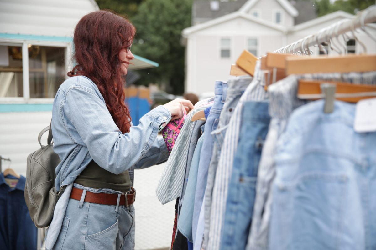 Caitlin Wilson looks through a rack of denim clothing at the Iowa City Flea Market at the PS1 Close House in Iowa City on Sunday Aug. 13, 2023. Many current fall trends center around denim.