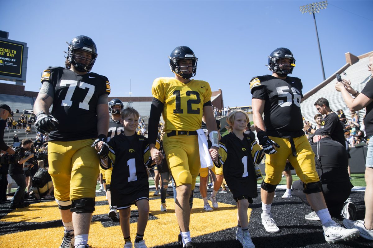 Kid Captains Atlas Coleman and Aiden Washburn walk onto the football field during Kid’s Day at Kinnick Stadium on Saturday, Aug. 10, 2024. Iowa football players signed autographs for young fans and held an open practice on the Kinnick field.