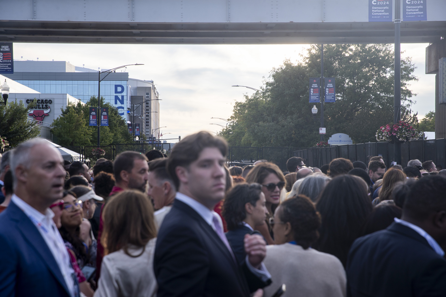 Delegates and other attendees wait outside of the safety perimeter of the United Center during the second day of the Democratic National Convention in Chicago on Tuesday, Aug. 20, 2024. Protesters also gathered around the outside of the perimeter.