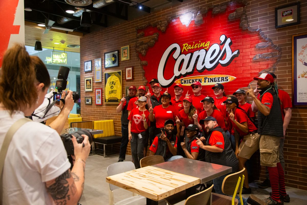 Employees pose for group portraits during the Cane’s opening on South Clinton Street in downtown Iowa City on Tuesday, Aug. 27, 2024. The opening included a raffle, a DJ, and free merchandise. 