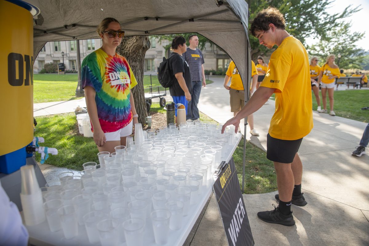 Freshmen University of Iowa students take free cups of water from event organizers during the 2024 Convocation on the Pentacrest on Sunday, Aug. 25, 2024.