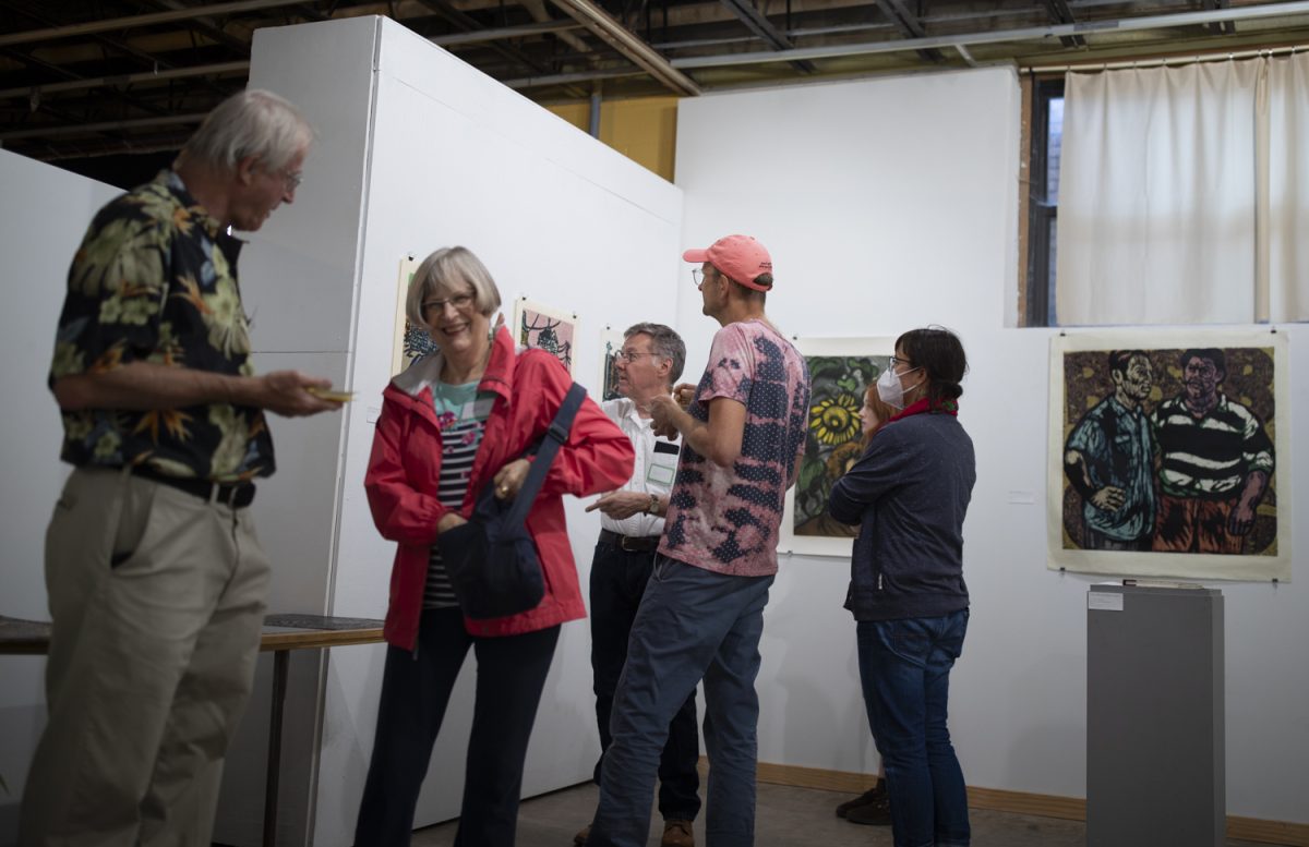 Attendees talk with David Johnson at his art exhibit hosted by ArtiFactory in Iowa City on Friday, Sept. 6, 2024. David earned his BFA in painting, drawing, and printmaking at the University of Iowa and later earned his MFA at the Cleveland Institute of Art.