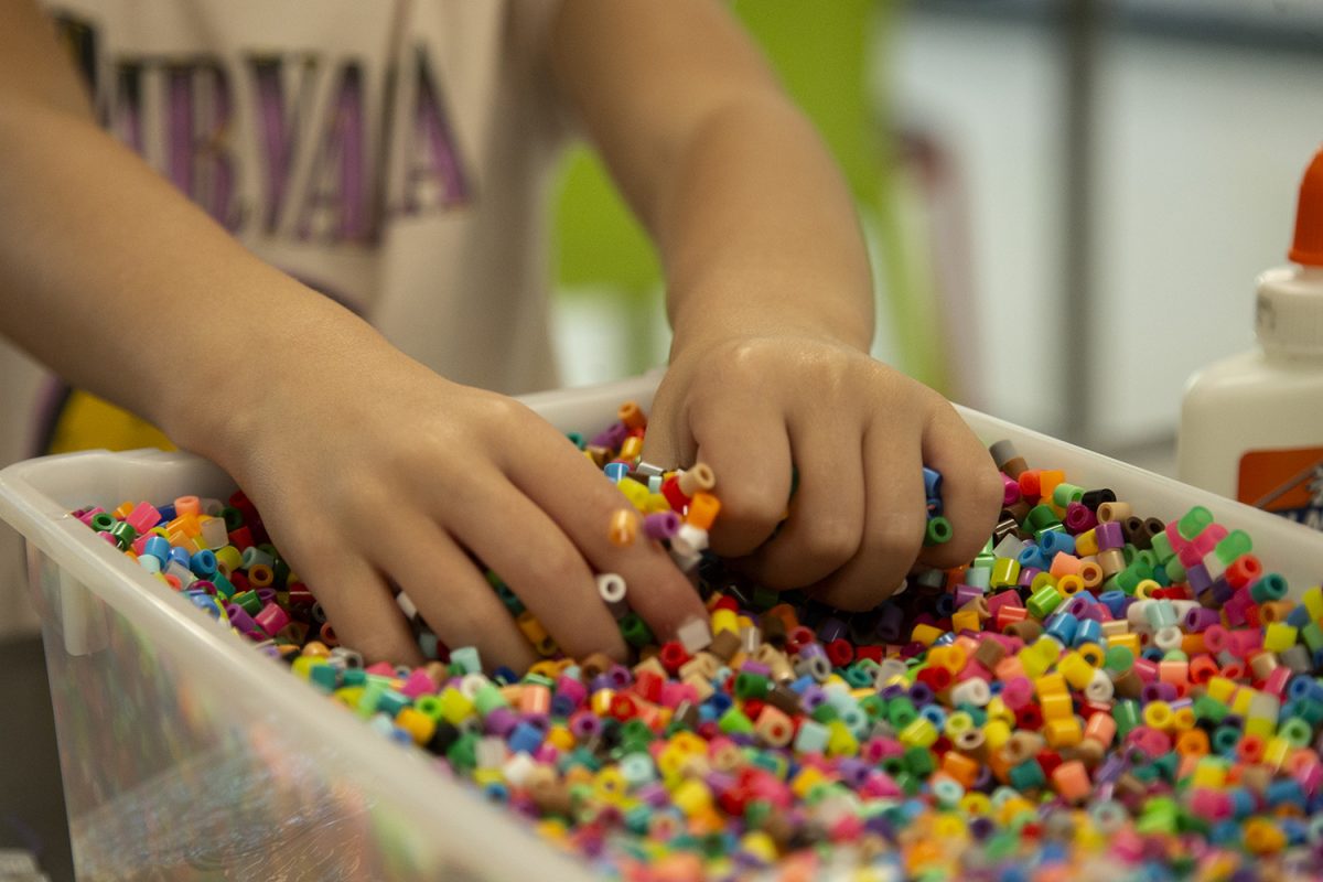 A child plays with beads during a Sensory Saturday event at the Robert A. Lee Community Recreation Center on Saturday, Sept. 7, 2024. Attendees glued various sensory objects like feathers, googly eyes, beads, fabric, and paper to popsicle sticks.