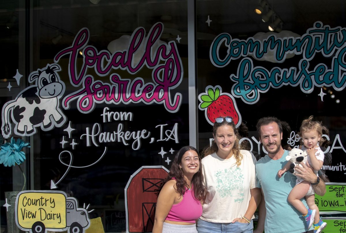 The Tessler and Bruner family stands outside Yotopia’s decorated windows with Assistant Manager Carma Abu-Ghazalah on Tuesday, Sept. 10, 2024. Yotopia is one of 17 small food businesses that was awarded with a Johnson County Farm Grant.