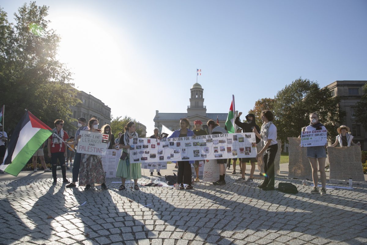 Protesters hold up signs displaying past protests in Iowa City for International Day of Action for Palestine by Iowans for Palestine at the Pentacrest in Iowa City on Oct. 5. During the protest, speakers led chants, and told personal stories.