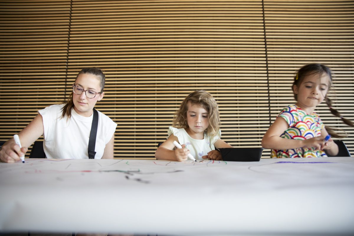 Elli, 4, (middle) and Izzy, 5, (right) draw during a Stanley Creates Musical Mural event at the Stanley Museum of Art in Iowa City on Saturday, Oct. 5, 2024. During the event, children ran around after songs and drew in various areas on a large canvas.