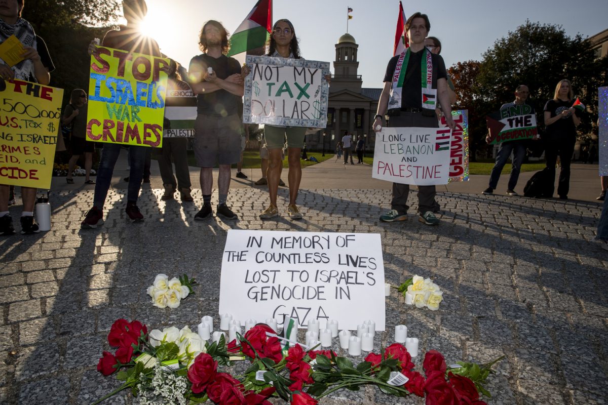 Attendees gather around a memorial during a vigil demonstration on the Pentacrest in Iowa City on Friday, Oct. 11, 2024. More than two dozen people were gathered on Clinton Street. (Cody Blissett/The Daily Iowan)