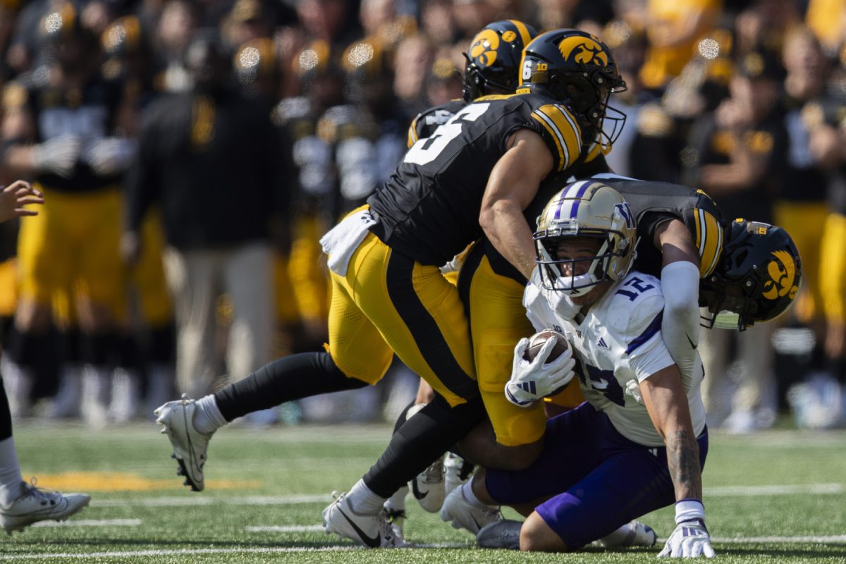 Washington safety Tristan Dunn is tackled by Iowa defensive back Zach Lutmer during a football game between Iowa and Washington at Kinnick Stadium in Iowa City on Oct. 12. The Hawkeyes defeated the Huskies 40-16.