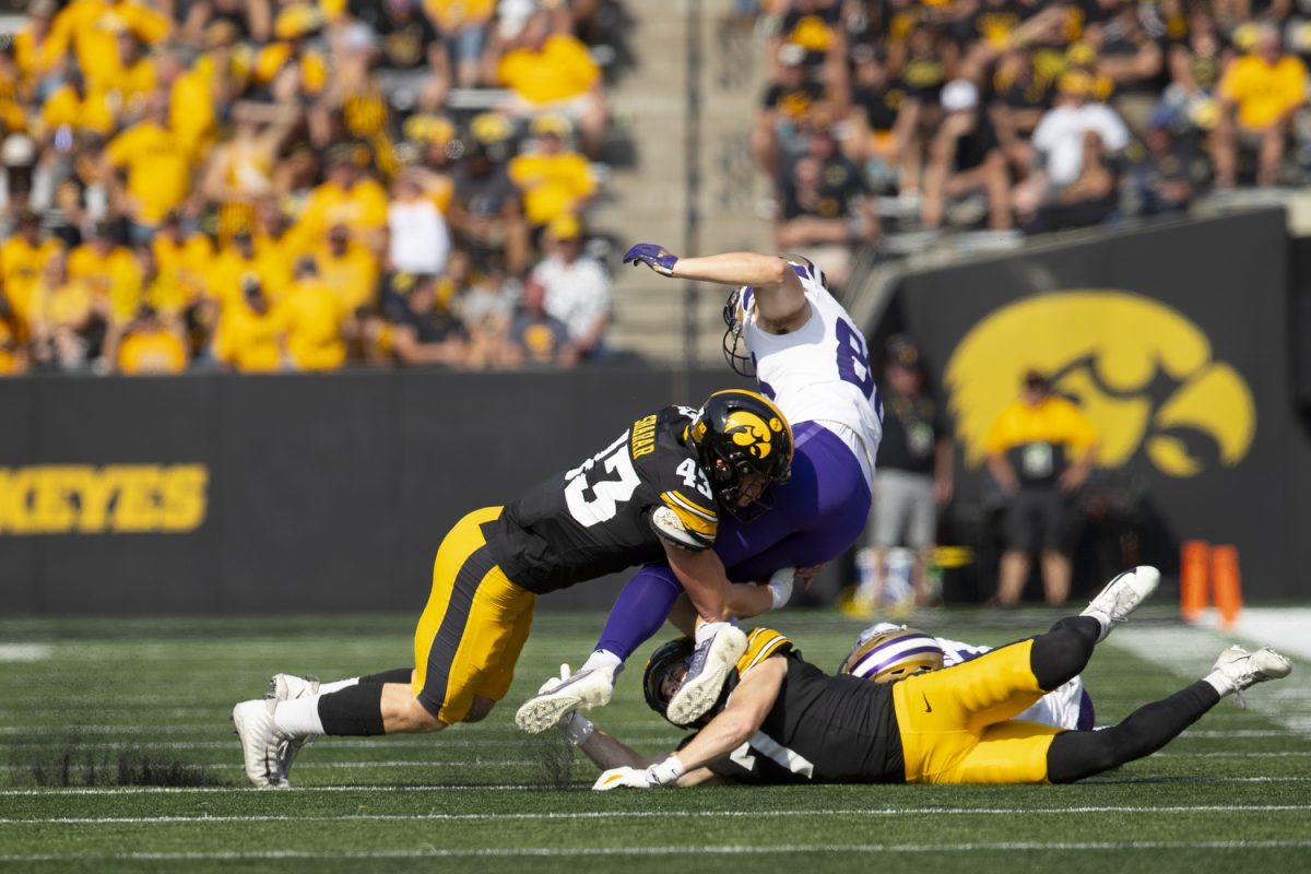 Iowa linebacker Karson Sharar and Iowa defensive back John Nestor tackle Washington Tight End Quentin Moore during a football game between Washington and Iowa at Kinnick Stadium in Iowa City on Saturday, Oct. 12, 2024. The Hawkeyes defeated the Huskies 40-16. (Emma Calabro/The Daily Iowan)