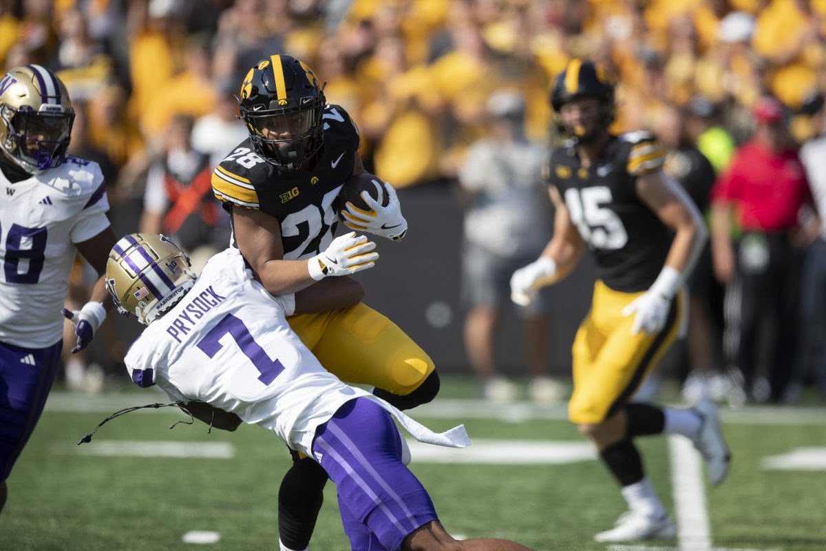 Iowa running back Kamari Moulton is tackled by Washington defensive back Ephesians Prysock during a football game between Iowa and Washington at Kinnick Stadium in Iowa City on Saturday, Oct. 12, 2024.