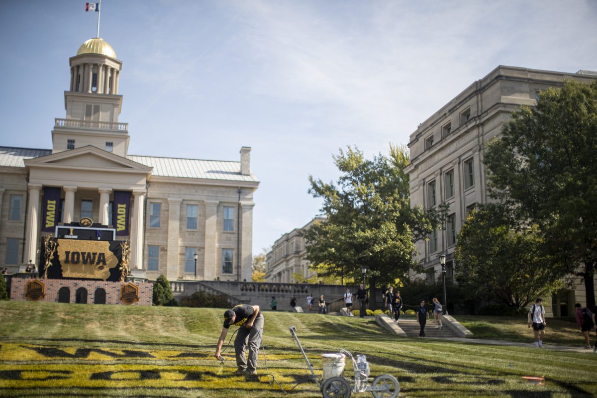 Andy Eiffert with Iowa athletics grounds maintenance, paints the grass on the Pentacrest in Iowa City, on Oct. 21. Painting began in the morning and finished up in the late afternoon. 