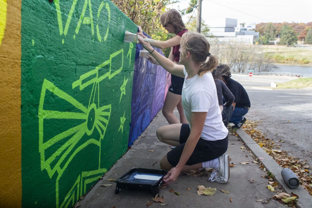 Alexander Barloon and fellow students paint a mural down the block of Brown Street for Resilient Sustainable Future for Iowa City on Oct. 29. The mural, “Grand Entrance,” depicts iconic images of Iowa City.