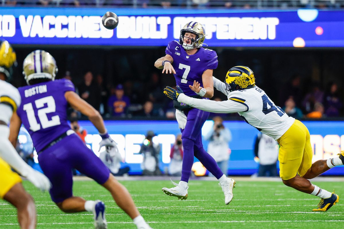 Oct 5, 2024; Seattle, Washington, USA; Washington Huskies quarterback Will Rogers (7) passes under pressure from Michigan Wolverines defensive end TJ Guy (42) during the third quarter at Alaska Airlines Field at Husky Stadium. 