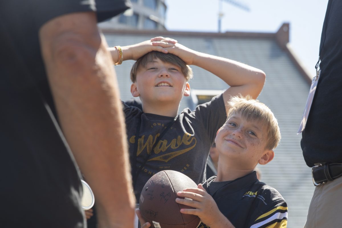 Kid Captain Hunter Mickelson (front) smiles as Iowa head coach Kirk Ferentz speaks with him during Kid’s Day at Kinnick Stadium on Saturday, Aug. 10, 2024. Iowa football players signed autographs for young fans and held an open practice on the Kinnick field.