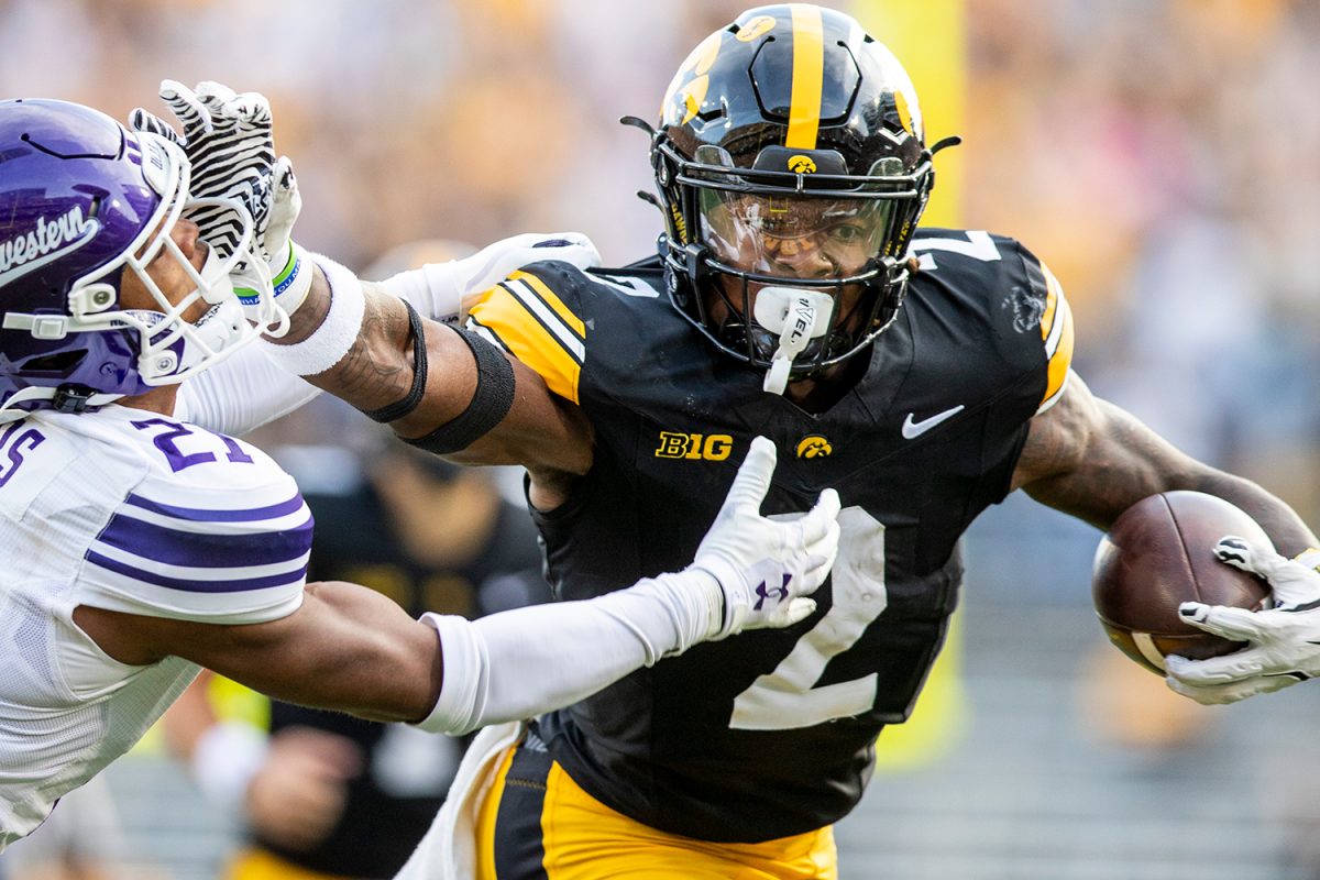 Iowa running back Kaleb Johnson stiff arms Northwestern defensive back Damon Walters before running into the endzone during a football game between Iowa and Northwestern at Kinnick Stadium on Oct. 26. Johnson averaged 7.8 yards per carry, scoring three touchdowns and totaling 109 yards. Johnson now has 16 rushing touchdowns for the season. Following the first half the Hawkeyes lead the Wildcats, 12-7.