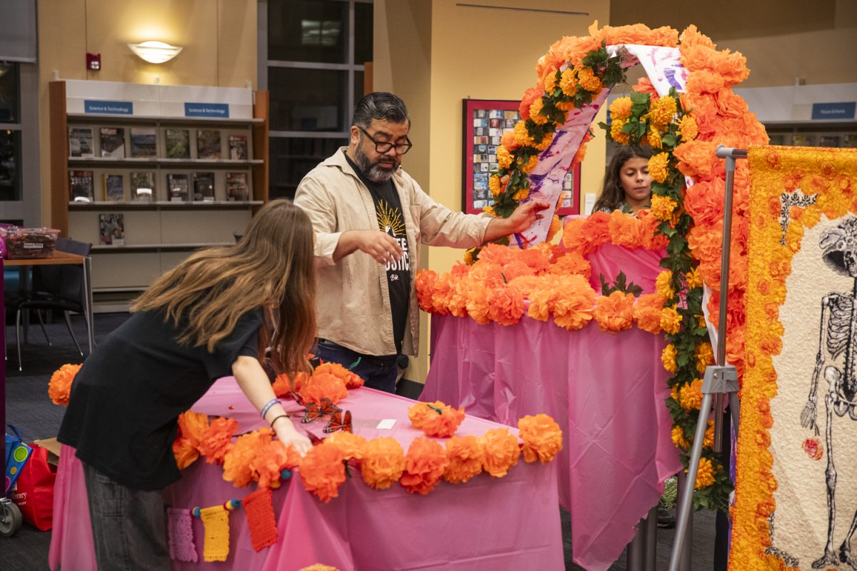 Manny Gálvez arranges decorations during the construction of an ofrenda for Día de Muertos at the Iowa City Public Library on Oct. 30. The altar to the dead stayed up until November 2.