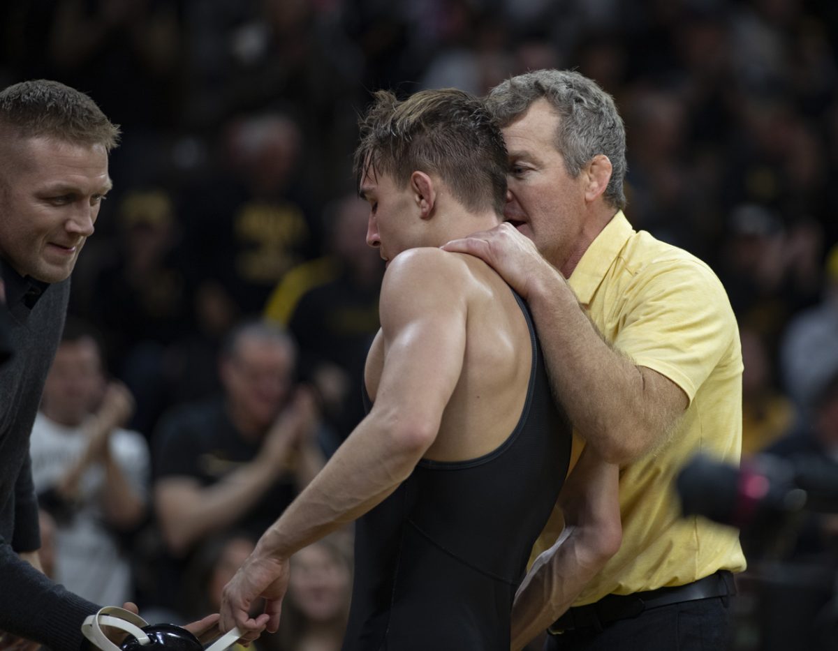 Iowa’s No. 9 133-pound Drake Ayala is congratulated by head coach Tom brands and asst. athletic trainer Jesse Donnewerth following his match during a Cy-Hawk men’s wrestling dual between No. 2 Iowa and No. 12 Iowa State at Carver-Hawkeye Arena in Iowa City on Saturday, Nov. 23, 2024. The Hawkeyes defeated the Cyclones 21-15.