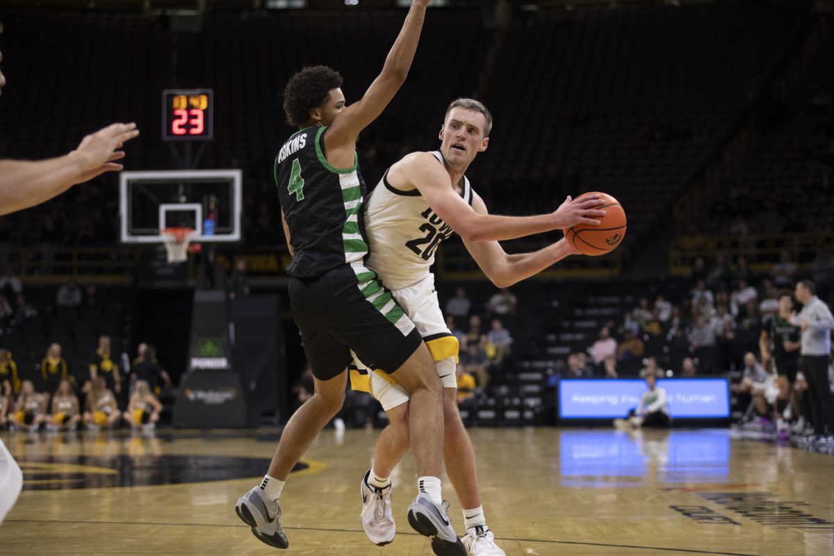 Payton Sandfort passes around Carmelo Adkins during a men’s basketball game between Iowa and USC Upstate at Carver-Hawkeye Arena in Iowa City, on Tuesday, Nov. 26, 2024. The Hawkeyes defeated the Spartans 110-77.