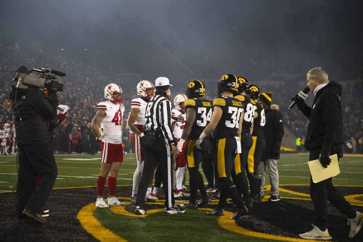 An official separates the Hawkeyes and Huskers for the coin toss before a football game between Iowa and Nebraska at Kinnick Stadium in Iowa City on Friday, Nov. 29, 2024. Iowa defeated Nebraska, 13-10.