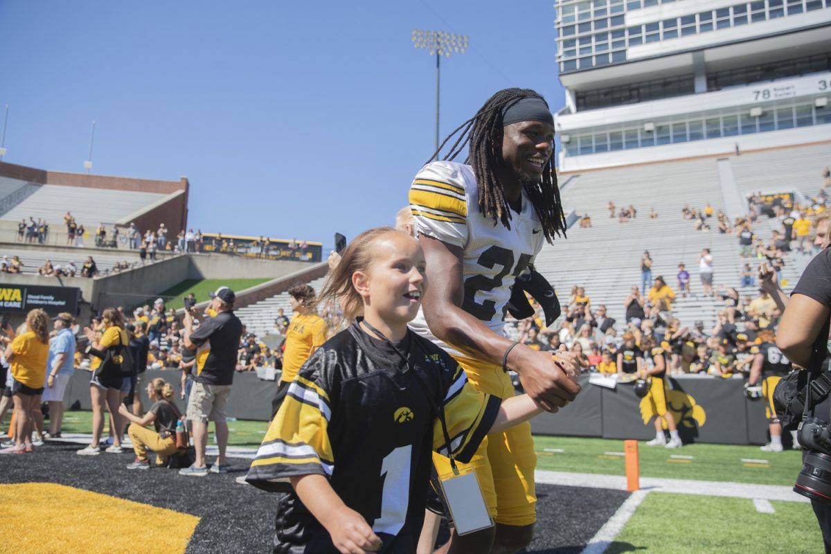 Kid Captain Raelyn Miller-Ramirez and Iowa defensive back Jermari Harris walk onto the football field during Kid’s Day at Kinnick Stadium on Saturday, Aug. 10, 2024. Iowa football players signed autographs for young fans and held an open practice on the Kinnick field.