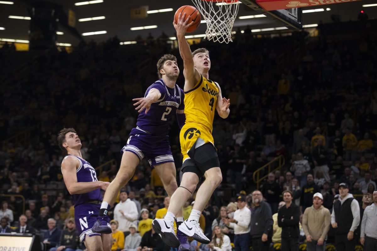 Josh Dix shoots a reverse layup while being contested by Nick Martinelli during an Iowa basketball game against the Northwestern Wildcats on December 3rd at Carver-Hawkeye Arena in Iowa City, Iowa. This was the first Big-Ten matchup for the Hawkeyes, who came out with a last second win over the Wildcats, 80-79.