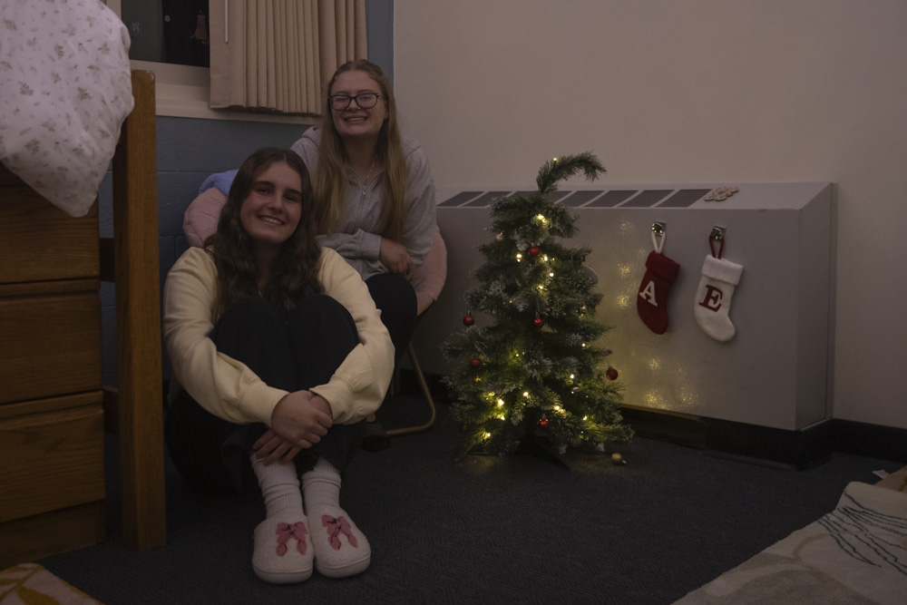 Emily Knowles and Ava Mandle pose for a portrait by Christmas decorations in their dorm at Mayflower Residence Hall on Dec. 9. Many students like to put up holiday decorations in their dorms to celebrate the festive season.