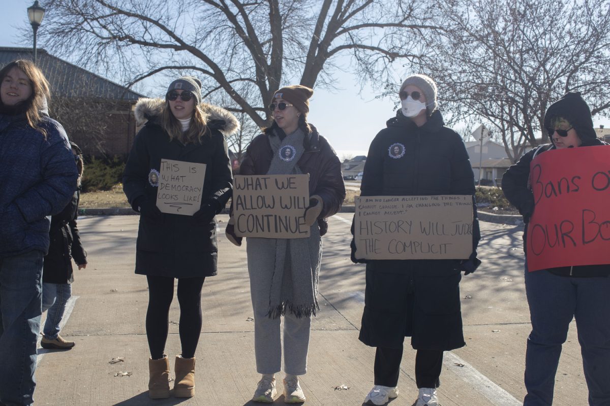 Attendees hold signs  during a singing circle and people’s march at the Coralville Public Library on Saturday, Jan. 18, 2024. The event was part of a string of nationwide People’s Marches in response to an upcoming Trump administration. Over 115 people attended the event, gathered in song, and marched around the area.