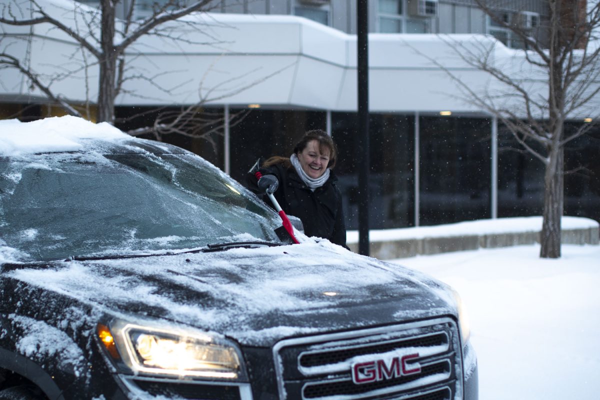 A woman cleans off her car during a snowstorm on the UI campus in Iowa City on Wednesday, Feb. 12, 2025. Multiple professors cancelled class after Iowa City reported an expected 6-9 inches of snow.