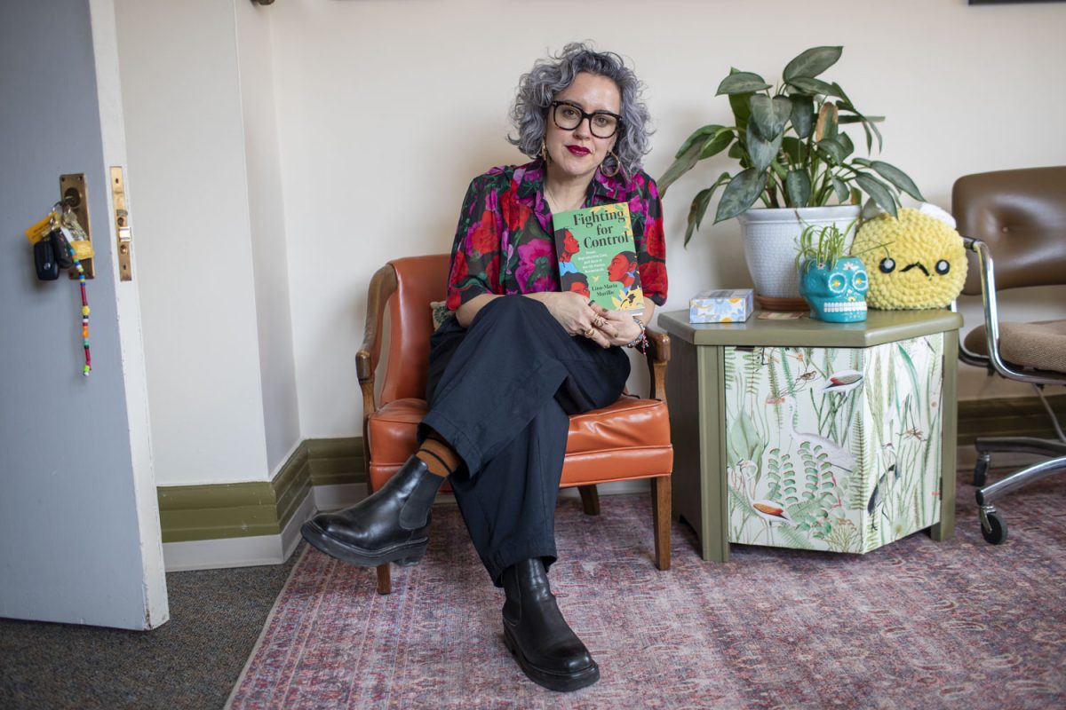 Dr. Lina-Maria Murillo poses for a portrait in her office at the Jefferson Building with her new book, “Fighting for Control: Reproductive Care, Race, and Power in the U.S.-Mexico Borderlands” on Friday, March 7th, 2025. Dr. Murillo is an assistant professor of Gender, Women’s and Sexualities Studios as well as History at the University of Iowa.