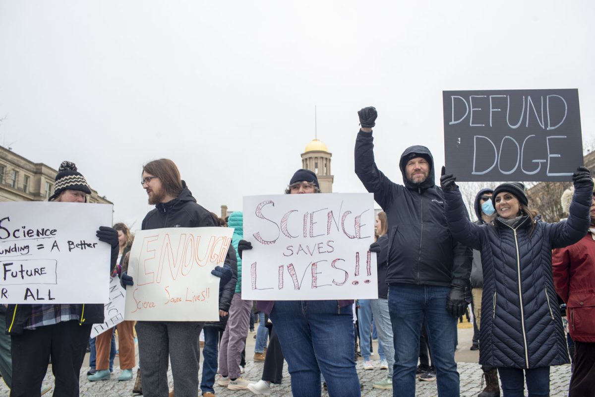 Attendees hold up homemade signs and cheer at supportive passersby during a Stand Up For Science rally on Friday, March 7, 2025. The rally was one of many being held nationally to protest against the Trump administration’s “censorship and political interference” in scientific research. Speakers at the event encouraged attendees to chant, cheer, and call their representatives. Live music was performed by the band Second Half.