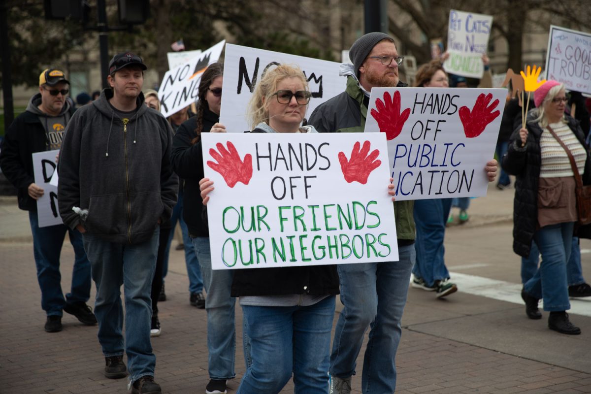 Protesters holds a sign during the “Hands Off!” protest in downtown Iowa City on April 5, 2025. This was a part of a nationwide anti-Trump protest and over a thousand attendees showed up.