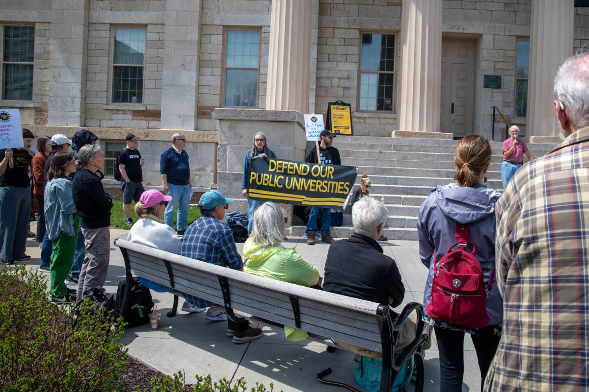 Protestors hold up posters and listen to Christopher Merrill, the director of the International Writing Program, during the Teach-In &amp; Speak Out event at the Pentacrest on Thursday, April 17, 2025. The protest was organized by the American Association of University Professors, COGS, and Standing Up For Science, and featured speakers who discussed the importance of free speech in education and the safety of international students.