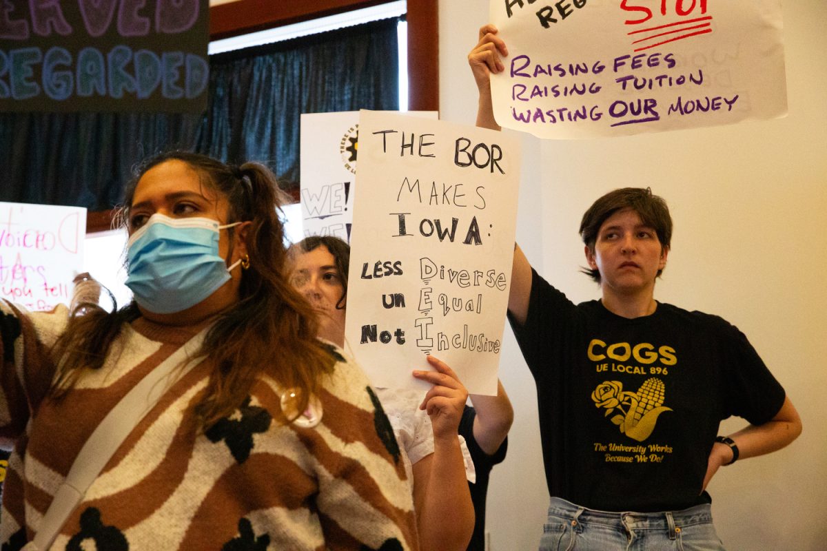 Protesters hold up signs during a board meeting in Ames, Iowa on April 23, 2025.