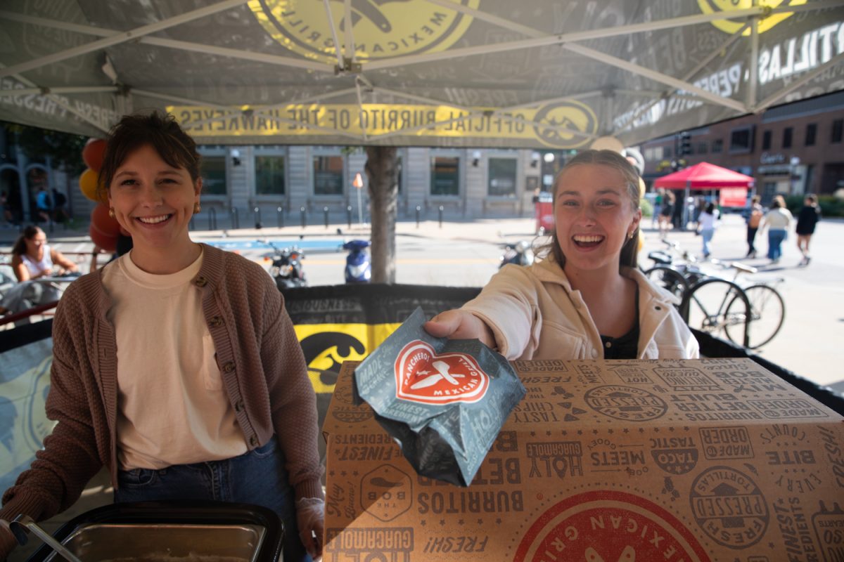 Servers at the Pancheros stand extend a meal at the camera at the Taste of Iowa City event on Wednesday, Aug. 27, 2025. The free tickets were sold out after an hour, with over a hundred students and community members exchanging tickets for meals at restaurant stands downtown.