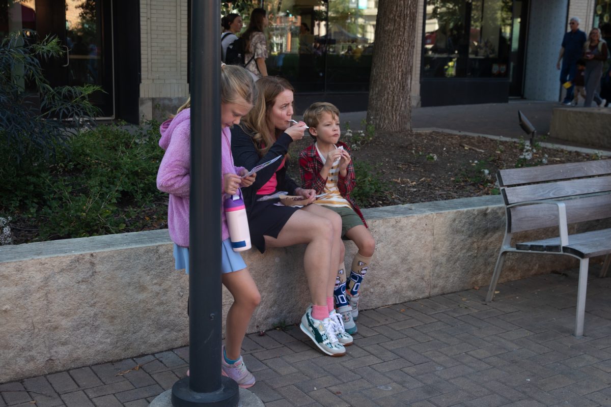 A family eats food during the Taste of Iowa City event on Wednesday, Aug. 27, 2025. The free tickets were sold out after an hour, with over a hundred students and community members exchanging tickets for meals at restaurant stands downtown.