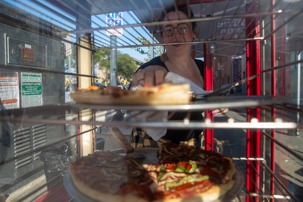 A server takes out a pizza at Scout’s Honor during the Taste of Iowa City event on Wednesday, Aug. 27, 2025. The free tickets were sold out after an hour, with over a hundred students and community members exchanging tickets for meals at restaurant stands downtown.