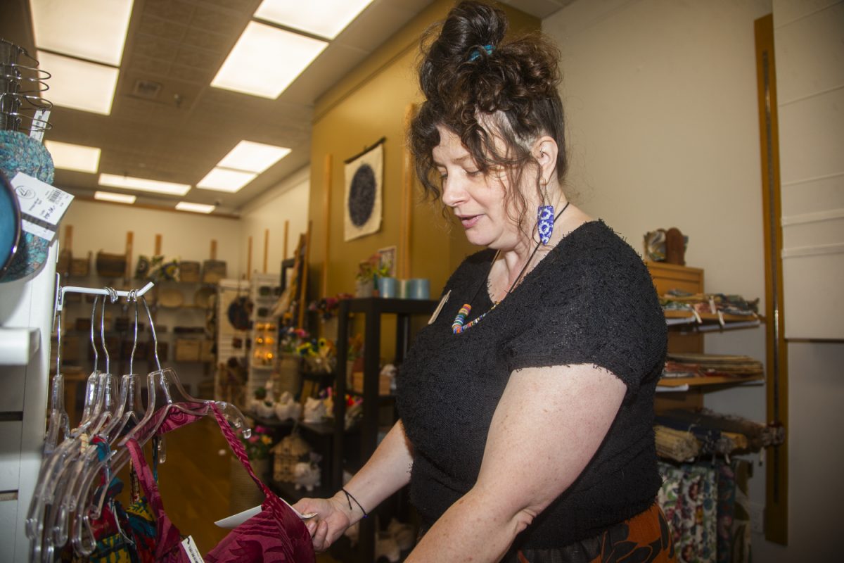 Executive Director Liz Preciado sorts through clothing at Mosaic Iowa City’s new location in the old Textiles storefront in downtown Iowa City on Saturday, Sept. 6, 2025. Preciado runs the store and serves as executive director to the board that oversees the local 501(c)(3) nonprofit after its departure from Ten Thousand Villages and into its new branding under Mosaic Iowa City.