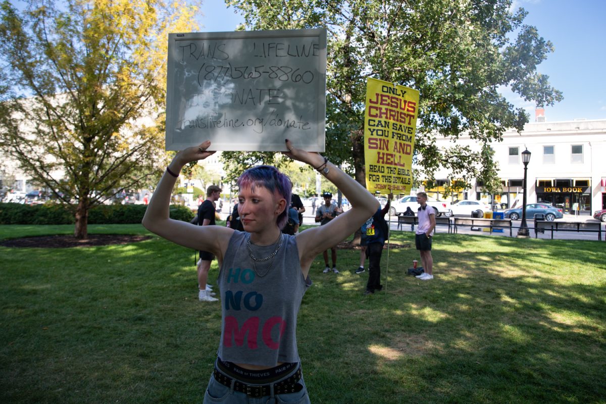 A protestor holds up a sign for the Trans Lifeline number in front of a religious speaker on Wednesday, Sept. 11, 2025. According to the Foundation for Individual Rights and Expression, or FIRE, the University of Iowa has a D- Free Speech Rating for the 2026 report.