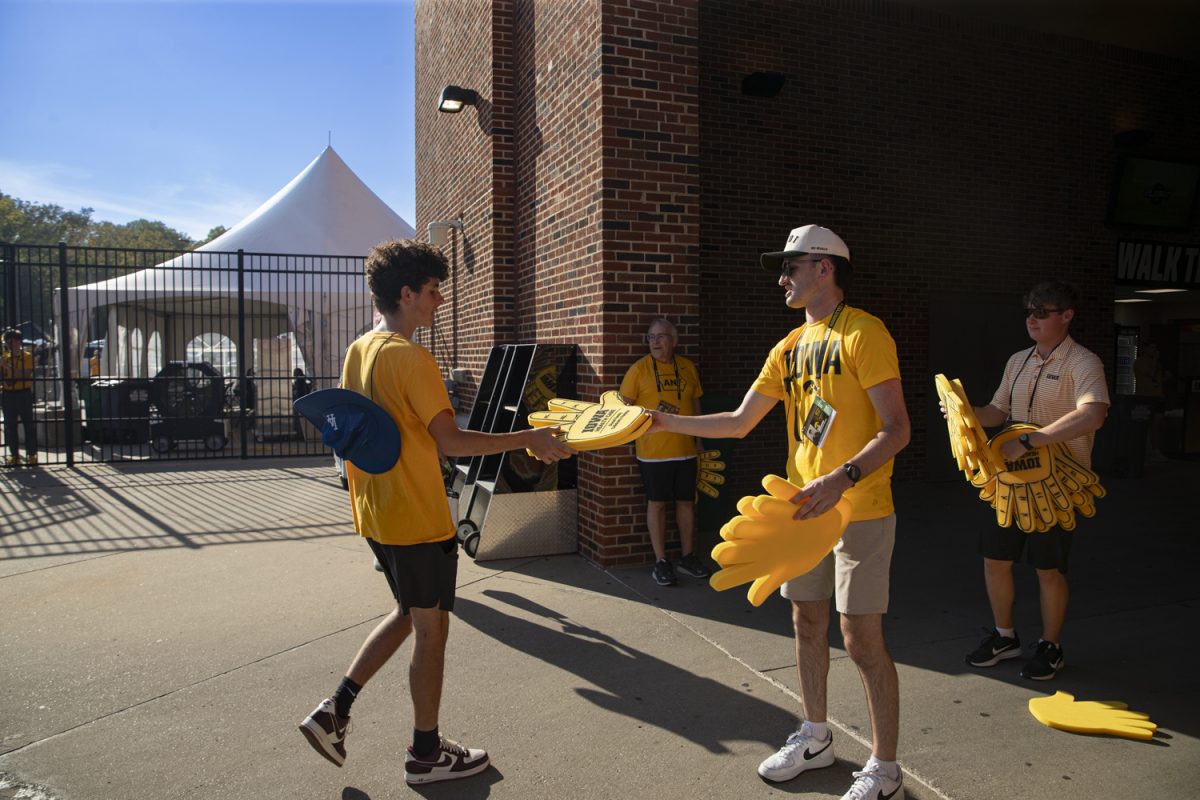 Stadium workers hand out foam hands prior to a football game between Iowa and the University of Massachusetts at Kinnick Stadium on Saturday, Sept. 13, 2025.