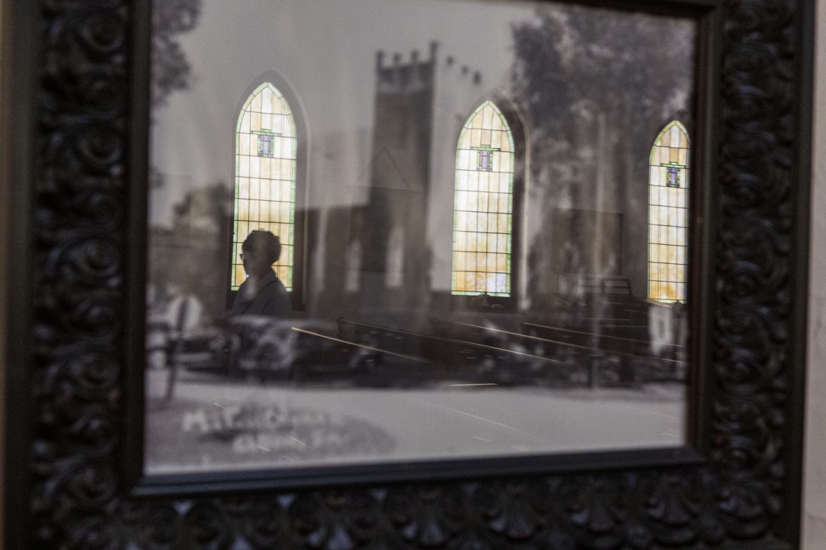 A member of Eldon United Methodist Church is seen walking by in the reflection of a photograph framed on the wall in Eldon, Iowa, on Sept. 20. A total of five people were in attendance that morning.