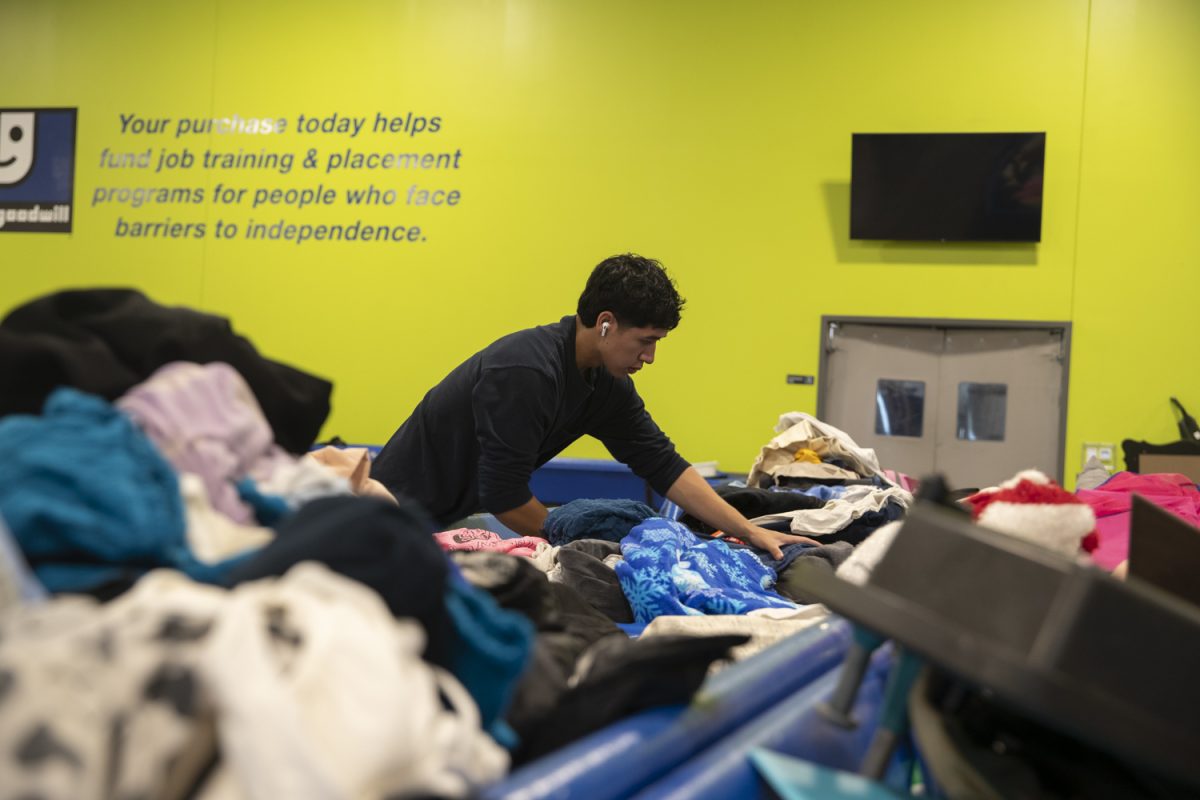 Romeo Diaz digs through clothes at the Goodwill Bins in Cedar Rapids, Iowa, on Monday, Oct. 13, 2025. Resellers frequent the bins to find cheap clothes and turn a profit.