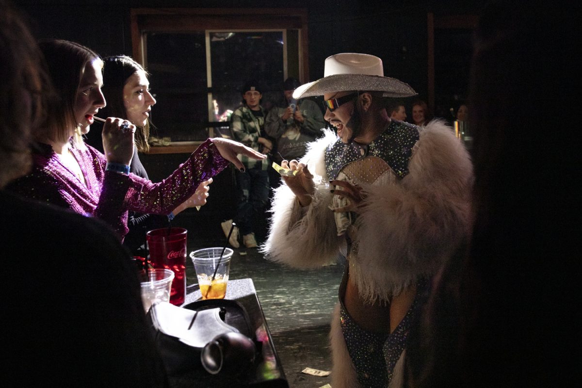 Patrons hand money to Southxrn Hxll during a performance at Studio 13 in Iowa City on Friday, Dec. 5, 2025. Hxll traveled from Wisconsin to perform in “TRANTASY,” the theme of the night at the bar.