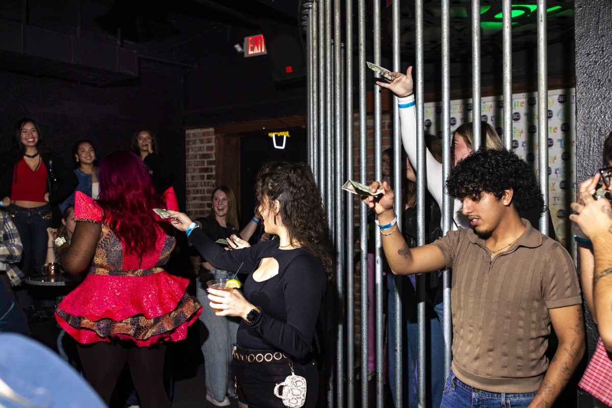 Patrons wait to hand money to Iiman Trinidad during a performance at Studio 13 in Iowa City on Friday, Dec. 5, 2025. (Emma Calabro/The Daily Iowan)